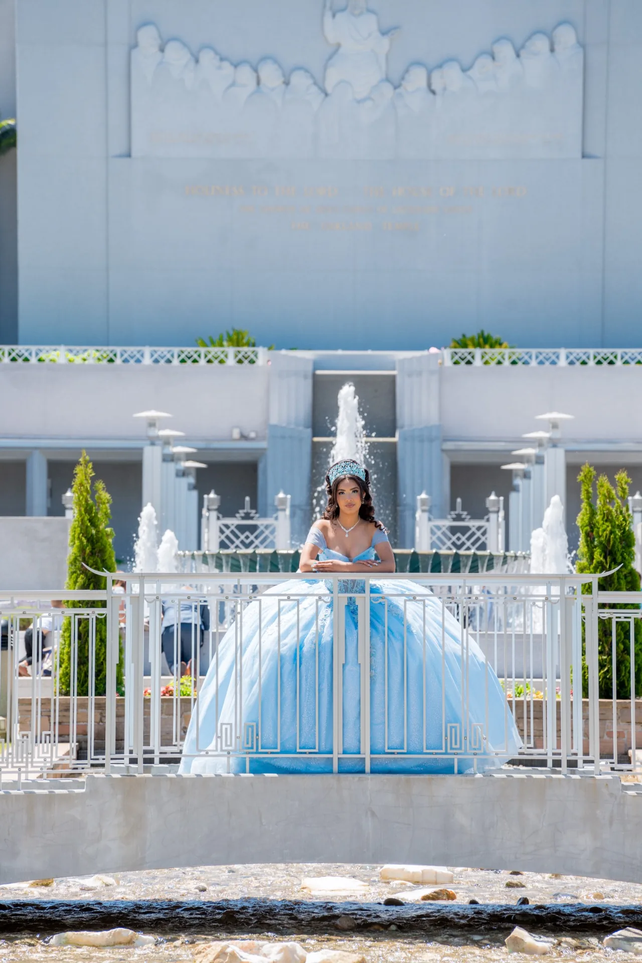 Quinceañera con vestido celeste entre las fuentes y la arquitectura simétrica del Templo de Oakland