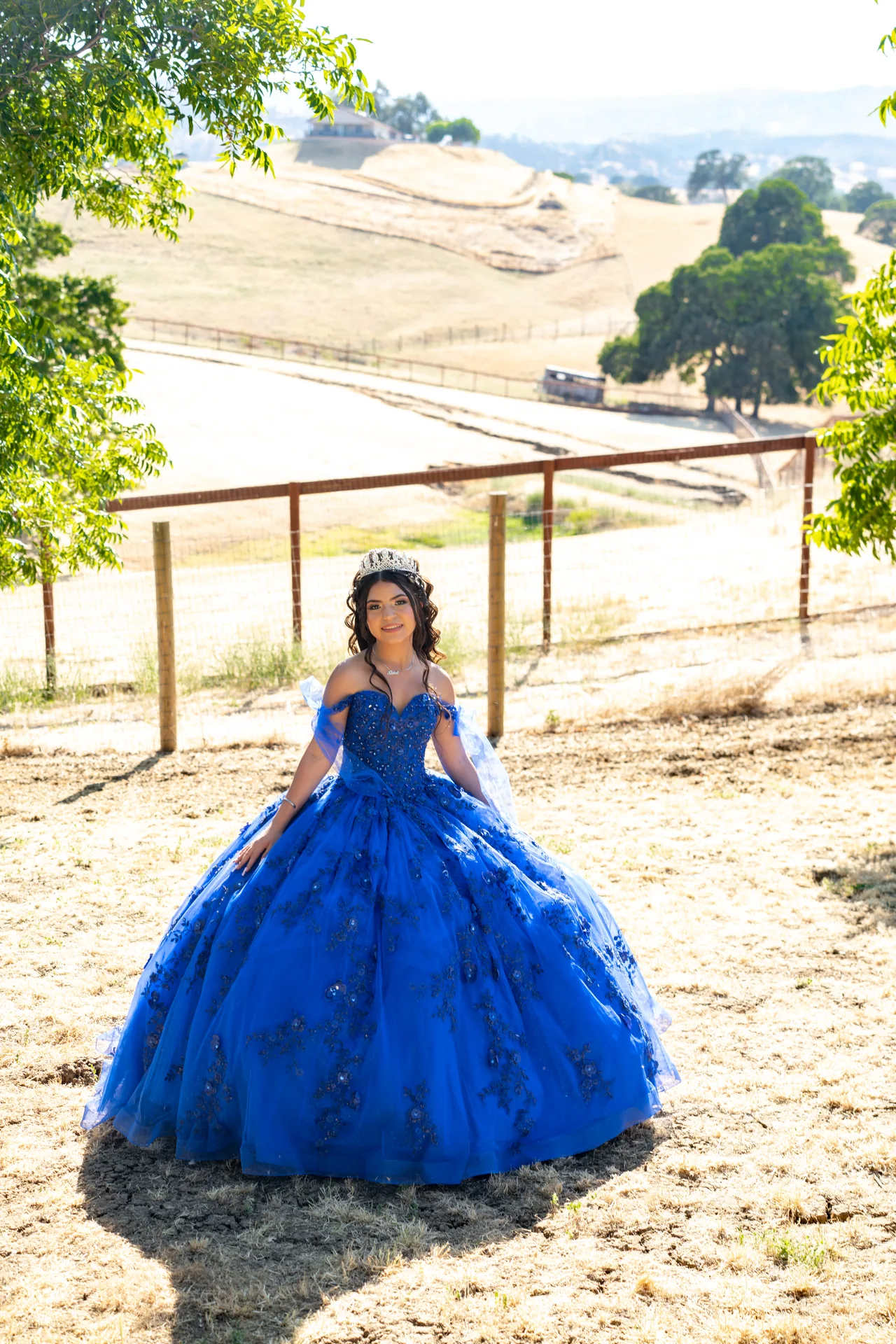 Quinceañera con vestido azul en un paisaje de campos dorados de Vacaville