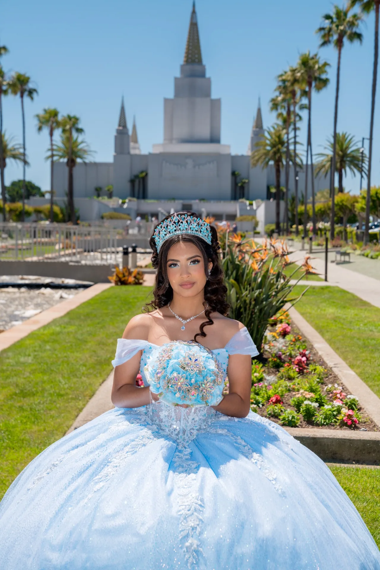 Quinceañera con bouquet frente a las palmeras y el Templo de Oakland
