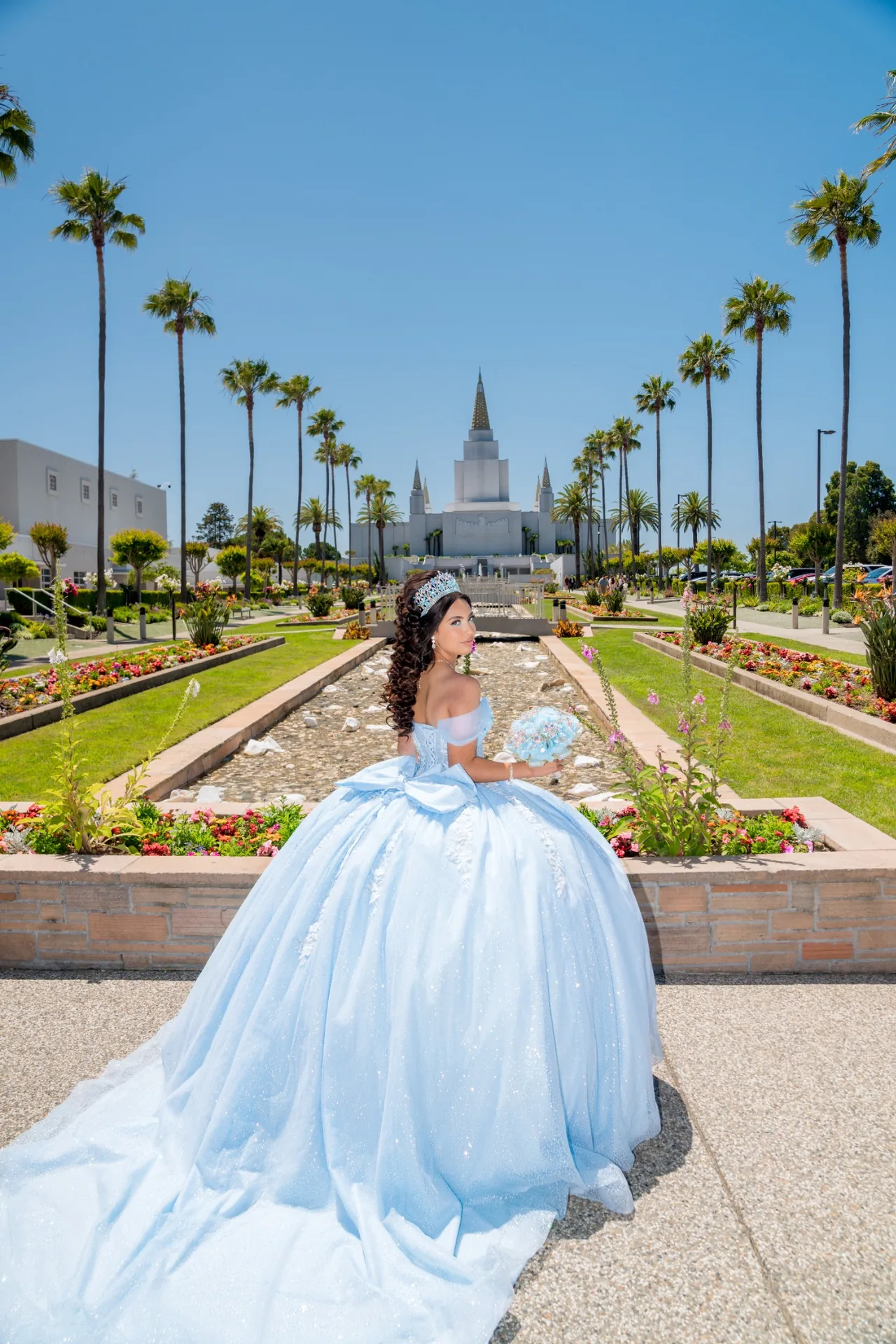 Quinceañera con vestido celeste en los jardines, palmeras y canal de agua del Templo de Oakland
