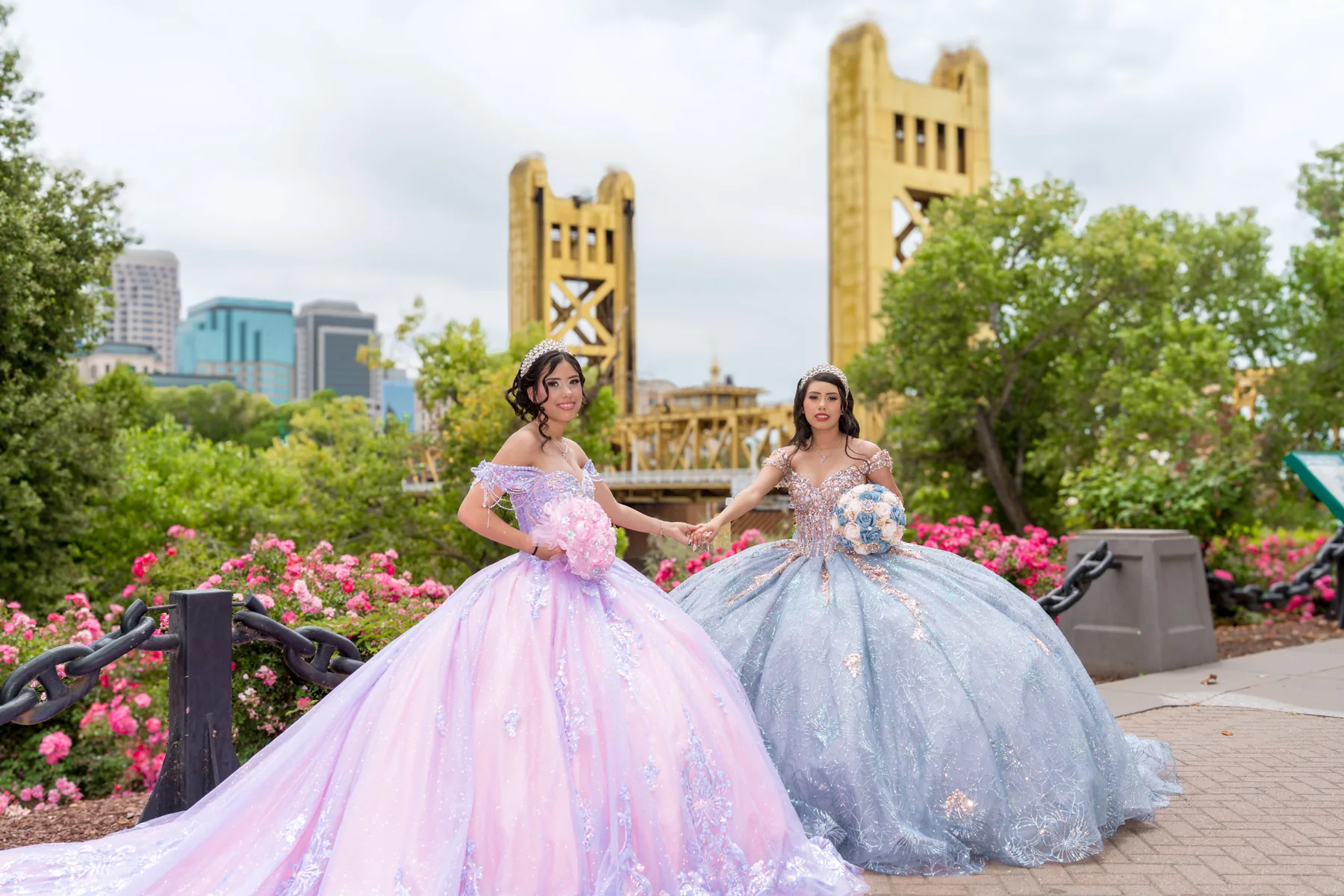 Dos quinceañeras con vestidos rosa y azul frente a Tower Bridge en Sacramento