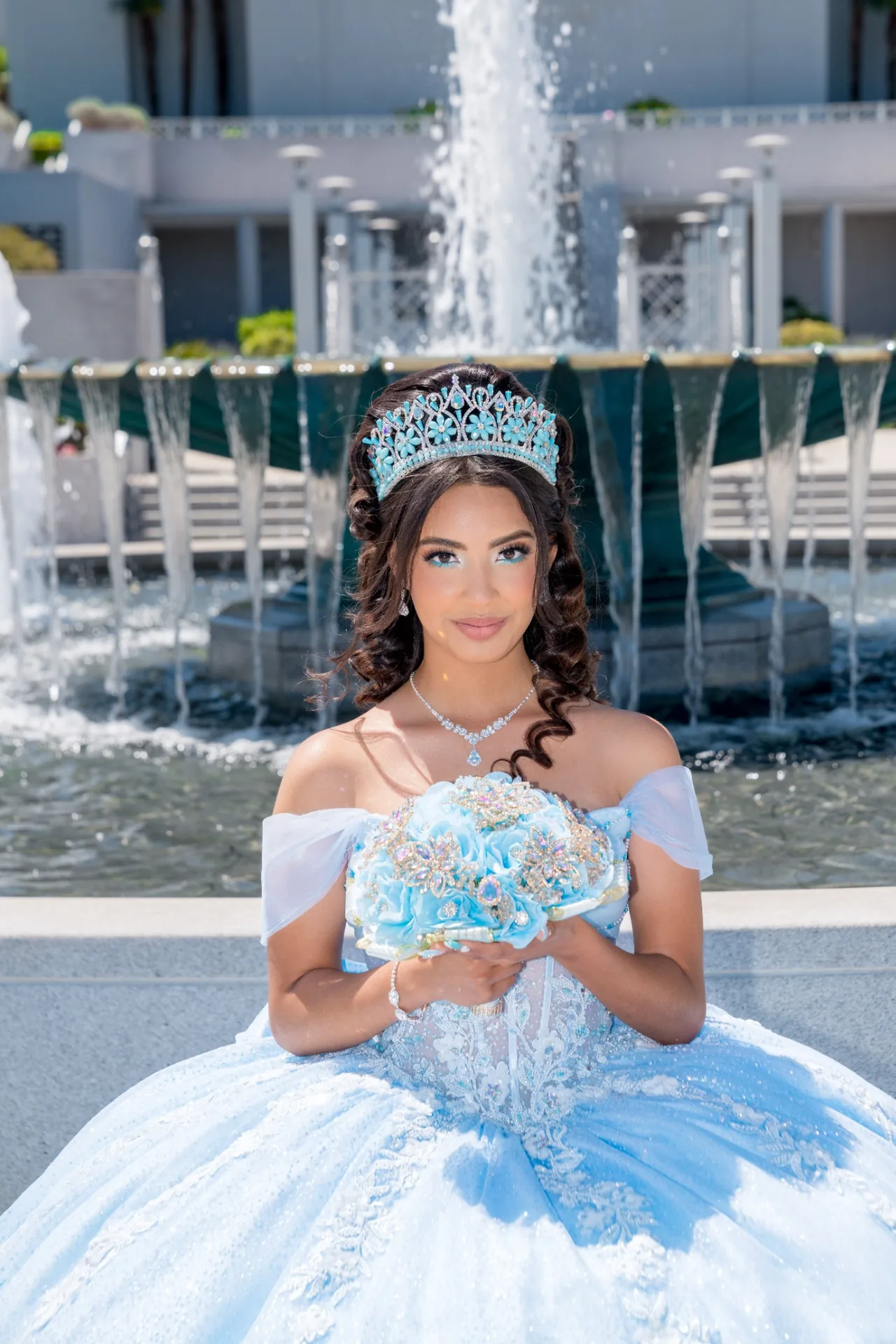 Retrato de quinceañera con bouquet celeste frente a las fuentes del Templo de Oakland